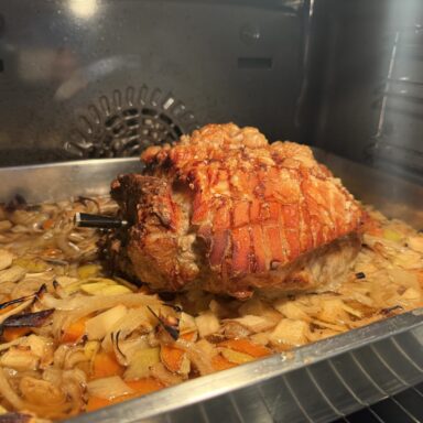 Krustenbraten mit knuspriger Schwarte auf Gemüsebett im Ofen